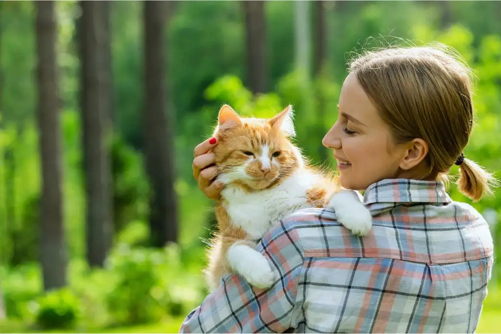 woman gently holding a cat near cattery